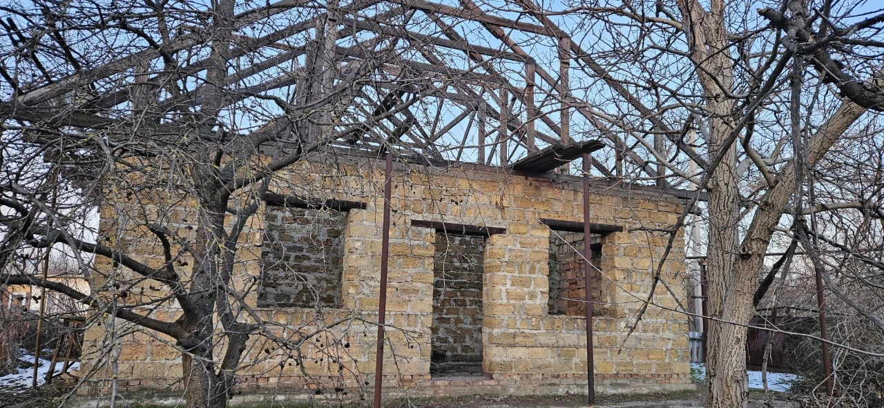 Large plot with an unfinished building and residential structure, suburb.