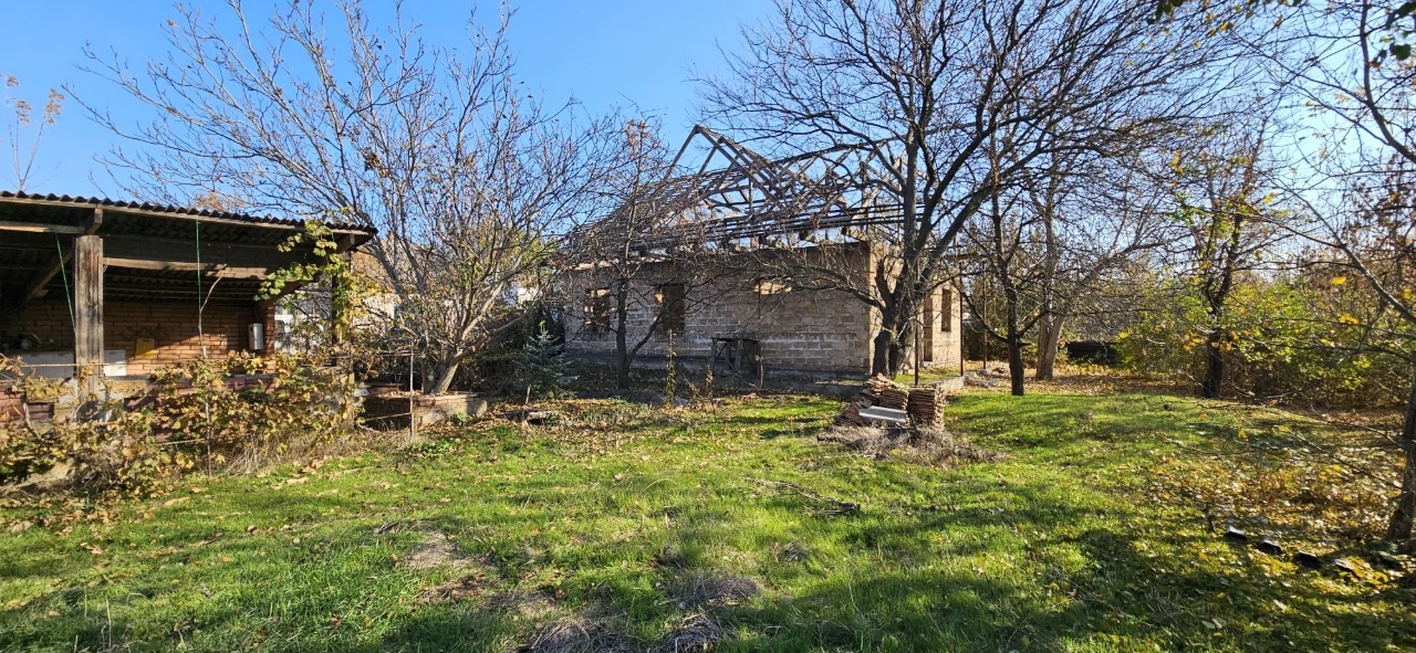 Large plot with an unfinished building and residential structure, suburb.