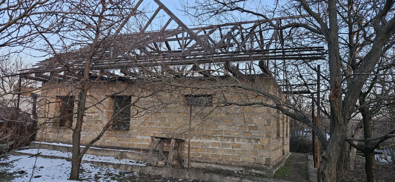 Large plot with an unfinished building and residential structure, suburb.