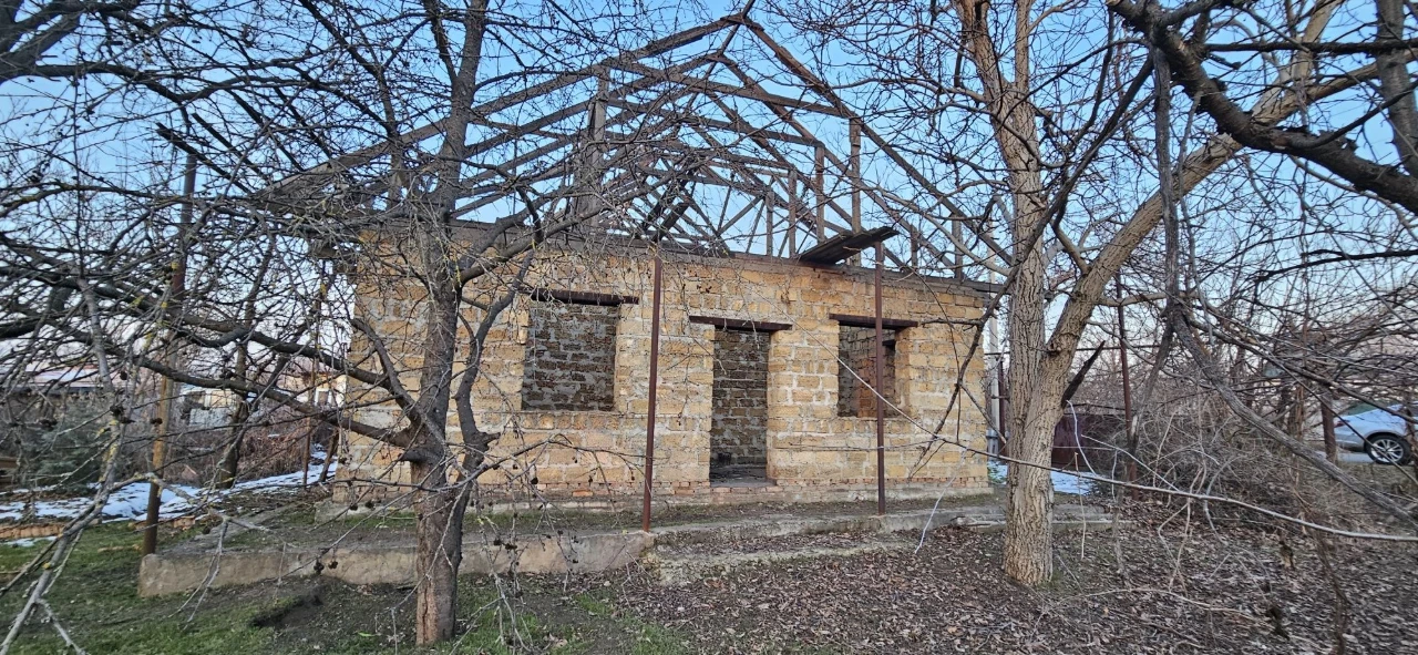 Large plot with an unfinished building and residential structure, suburb.