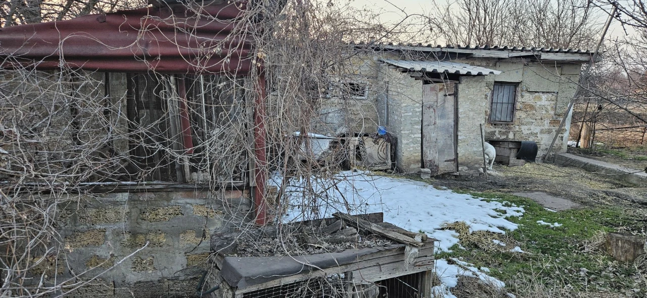 Large plot with an unfinished building and residential structure, suburb.