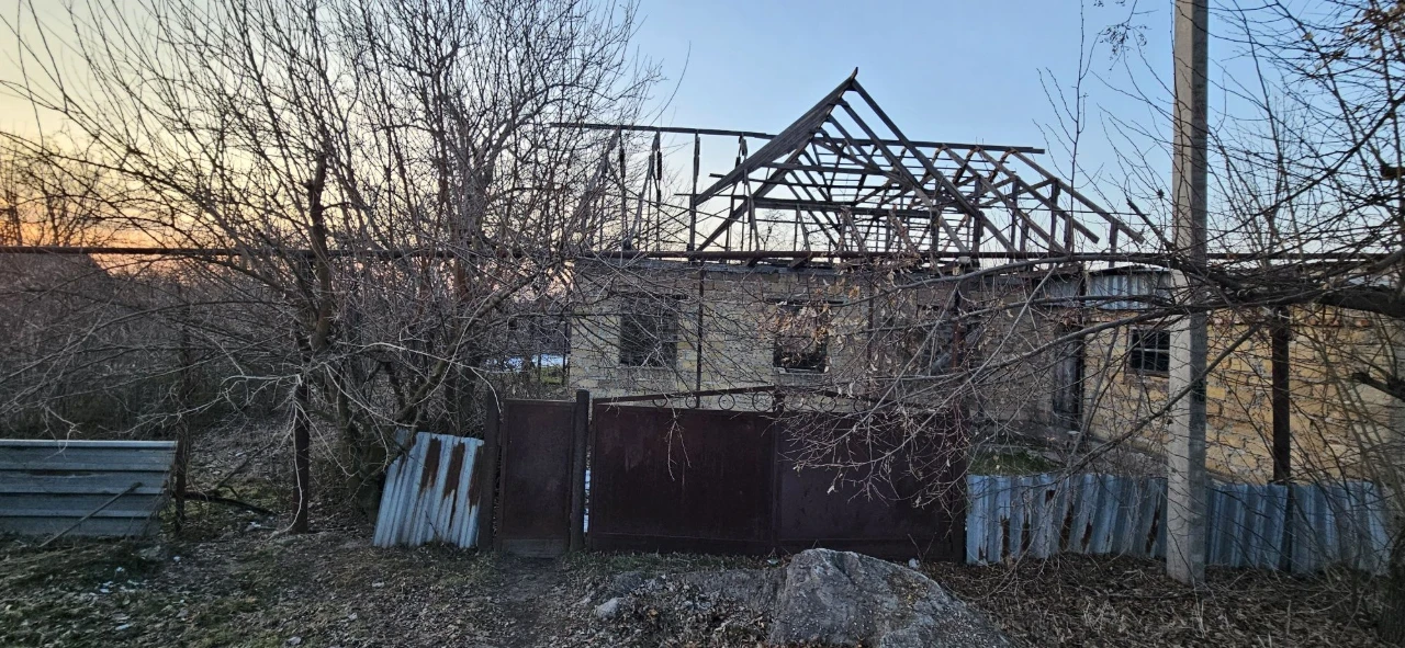 Large plot with an unfinished building and residential structure, suburb.